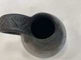 a black vase that is sitting on a white table