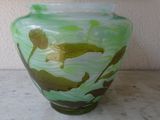 a green vase sitting on a table with a white wall in the background