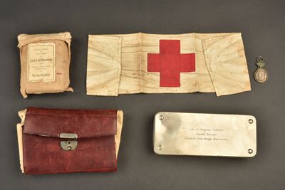 une vieille trousse de secours ornée d'une croix rouge, à côté d'autres objets