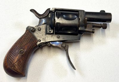 un vieux revolver avec une poignée en bois sur une surface blanche
