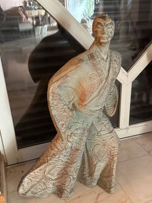 une statue représentant un homme debout devant une fenêtre