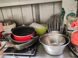 des casseroles et des poêles sont posées sur une cuisinière, avec un fouet et encore un fouet en arrière-plan