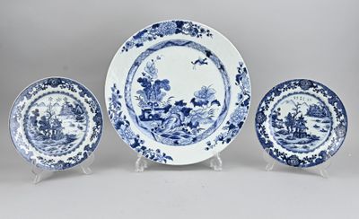 trois assiettes bleues et blanches et un porte-assiettes posés sur une surface blanche