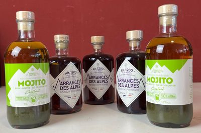 Des bouteilles d'huile d'olive et de vinaigre sont posées sur un plan de travail devant un mur rouge
