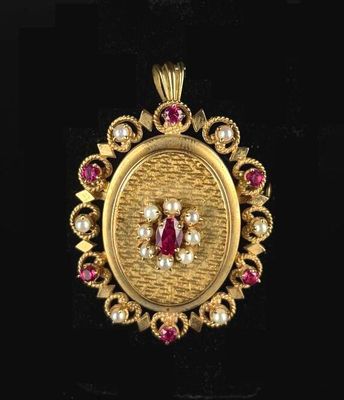 a close up of a gold pendant with a ruby and white stone