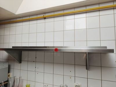 une photo d'une cuisine avec une étagère en acier inoxydable