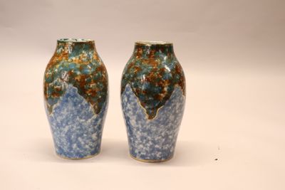 two vases sitting side by side on a white surface