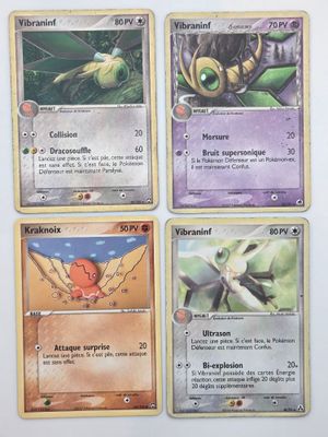Quatre cartes Pokémon sont représentées sur une surface blanche