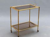 a gold metal and glass serving cart with two shelves
