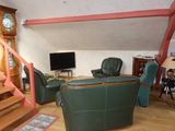 a living room with a green couch and a clock on the wall