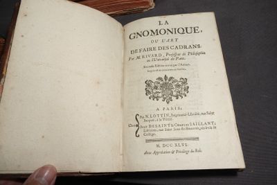 quelqu'un tient un livre ouvert sur une table devant laquelle se trouve une pile de livres