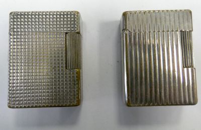 two silver cigarette cases sitting next to each other on a white surface