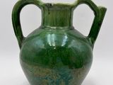 a green vase that is sitting on a white surface