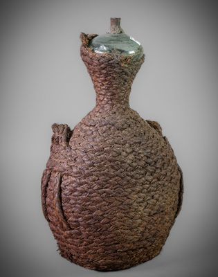 a brown vase with a green top sitting on a table