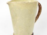 yellow and brown ceramic pitcher on wooden stand on white background