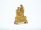 a gold clock with a statue of a man sitting on top of it
