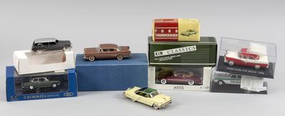Plusieurs petites voitures sont posées sur des cartons, sur une surface blanche.