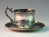 a silver cup and saucer sitting on a saucer