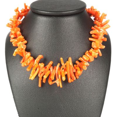 un gros plan d'un collier orné de perles orange sur un mannequin