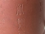 a brown vase with writing on it sitting on a table