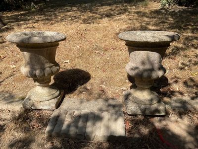 deux urnes en pierre posées à même le sol dans la cour