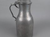 an old silver pitcher with a handle on a gray background