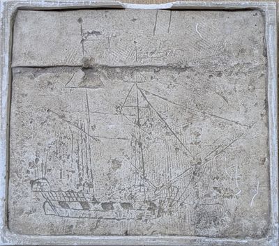 une plaque en pierre représentant un navire, située devant un bâtiment