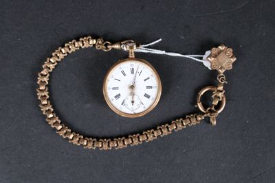 a gold watch with a chain around it on a black surface