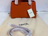 un sac à main orange et un sac blanc muni d'une étiquette