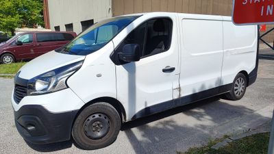 une camionnette blanche garée sur un parking à côté d'un panneau rouge