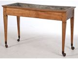 une vieille table en bois avec un plateau en marbre, montée sur roulettes
