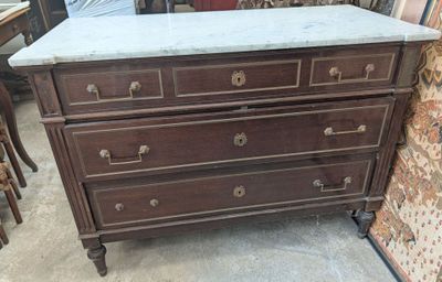 a marble top chest of drawers in the middle of a room