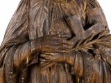 wooden statue of a woman holding a book and a book in her hands