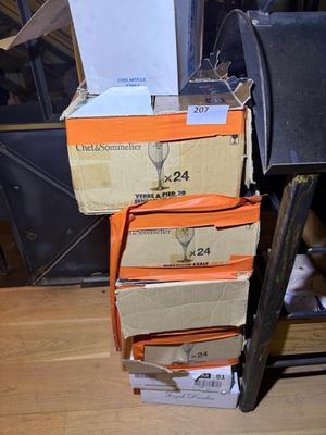 several boxes of wine glasses stacked on top of each other on a wooden floor