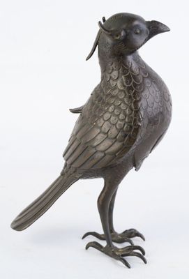 un oiseau en bronze posé sur une surface blanche