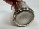 a person holding a silver cup on a white surface