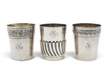 three silver cups with designs on them on a white background