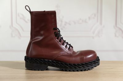 des bottes en cuir rouge à semelles noires posées sur une table en bois
