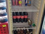 a refrigerator that has a lot of sodas and soda bottles in it
