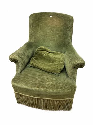 une chaise verte aux accoudoirs frangés, sur laquelle est posé un coussin