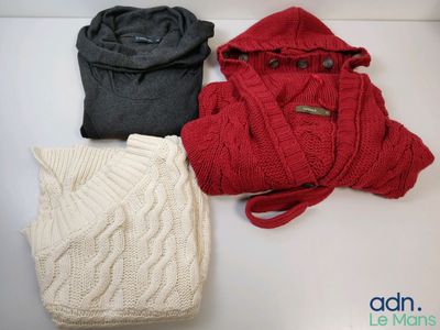 three sweaters and a hat are laid out on a table