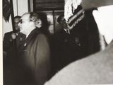 black and white photograph of a man in a suit and tie talking to a man in a suit and tie