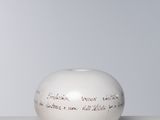 un vase blanc portant une inscription, posé sur une table