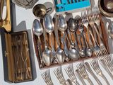 a tray with silverware and silver spoons on a table