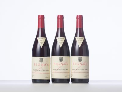three bottles of red wine sitting on top of a white table