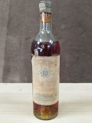 une vieille bouteille de vin posée sur une table, avec un mur marron en arrière-plan
