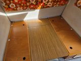 an image of the inside of a camper with wood flooring