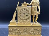 une statue représentant un homme tenant une horloge posée sur une table