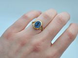 gold plated ring with a blue stone in the middle of the finger