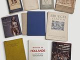 Plusieurs livres sont disposés sur une surface blanche, devant un fond blanc.